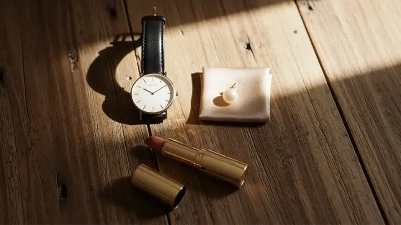 Close-up de tecido de linho bege e relógio dourado minimalista representando luxo silencioso.