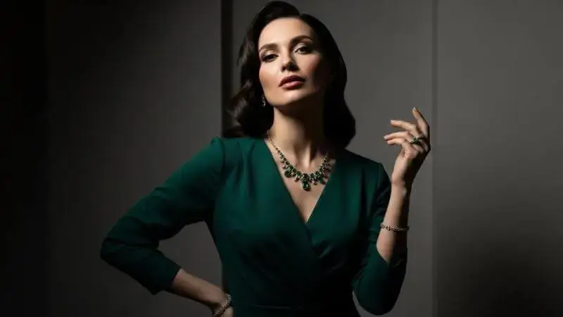 Mulher usando vestido verde esmeralda elegante e maquiagem leve.